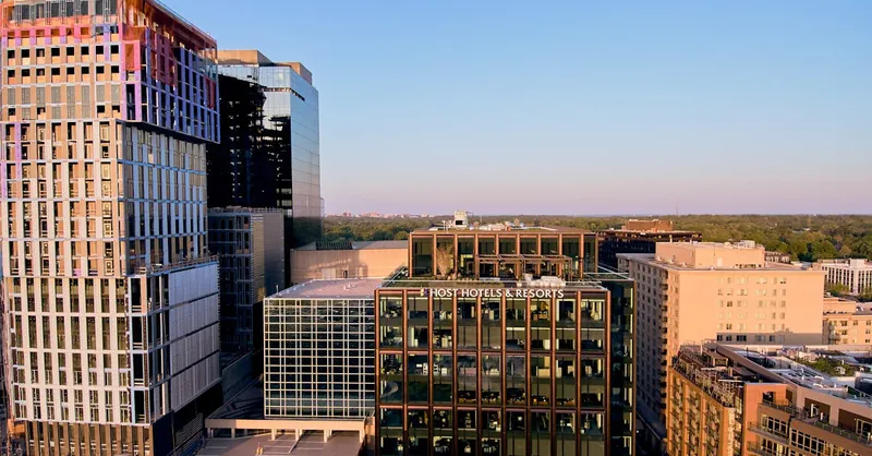 Aerial view of a modern cityscape featuring Host Hotels & Resorts during sunset, highlighting urban architecture.