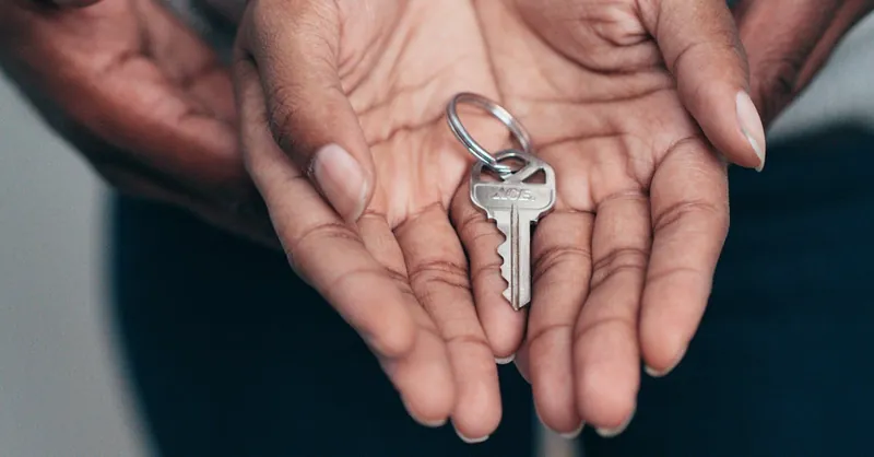 Close-up of hands holding a key, symbolizing homeownership, real estate, and property investment.