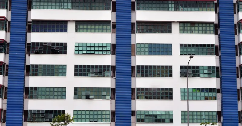Symmetrical urban building facade with blue panel accents and large windows.