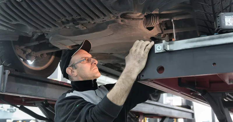 Professional mechanic conducting vehicle inspection in an auto workshop.