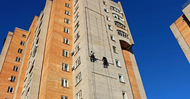 Tall high-rise building with workers performing maintenance on the facade.