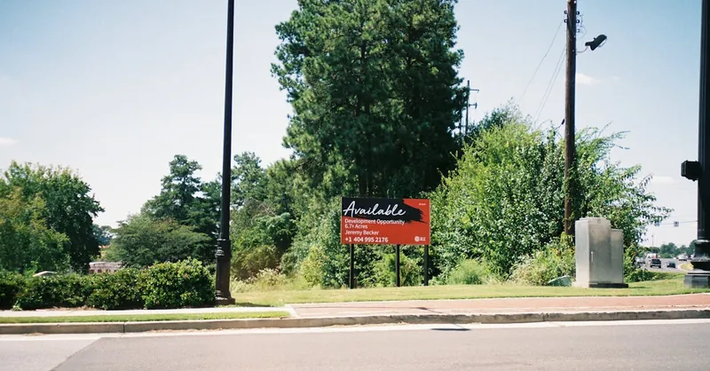 Vacant lot in Atlanta featuring a development opportunity sign amidst greenery.