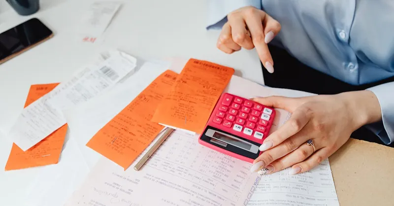 Businesswoman calculates expenses using receipts and calculator at desk. Ideal for finance, accounting themes.