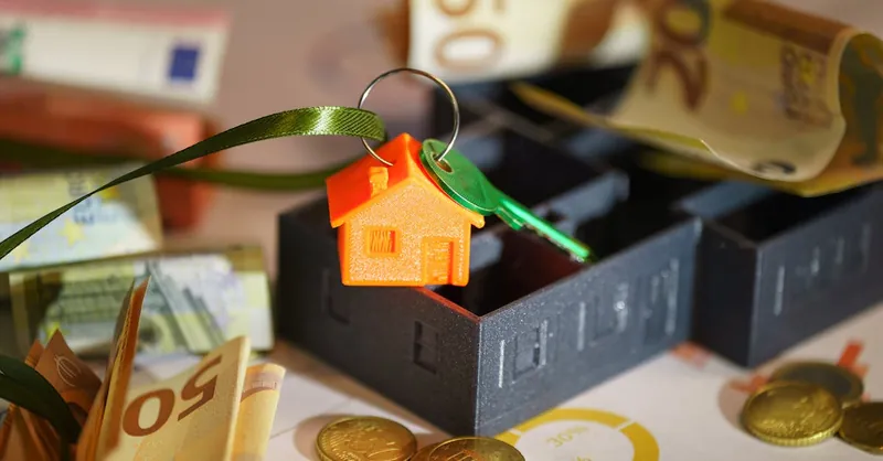 Image depicting real estate investment with keychain, euros, and financial charts.