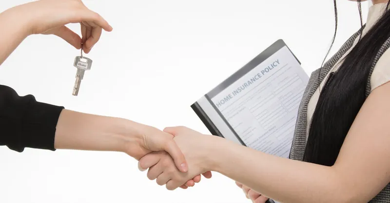 A real estate transaction with a handshake and key exchange, highlighting a home insurance document.