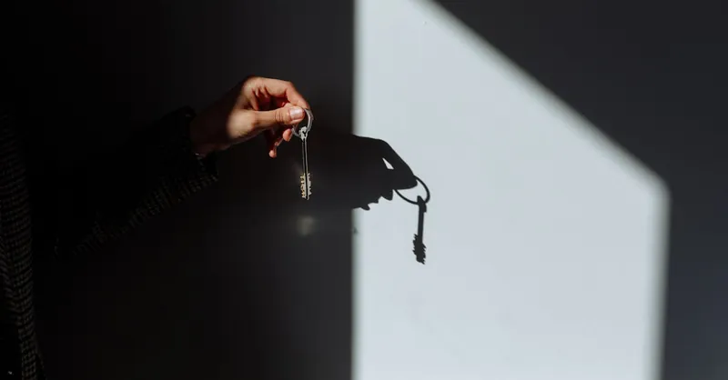 Minimalist photo of a hand holding a key casting a shadow, signifying property ownership