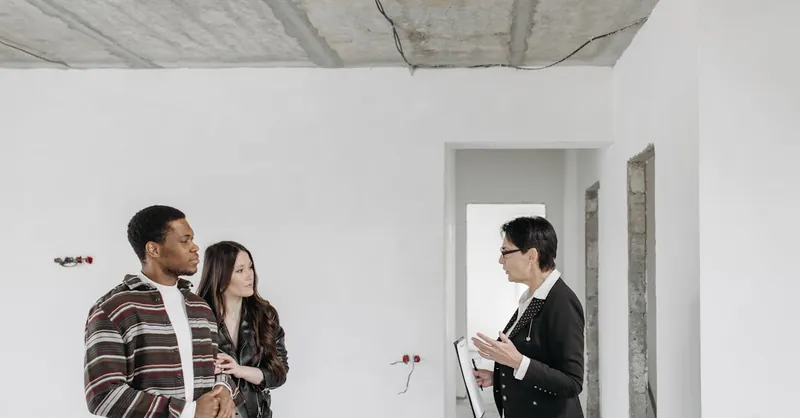 Real estate agent discussing property details with clients in an unfinished apartment.