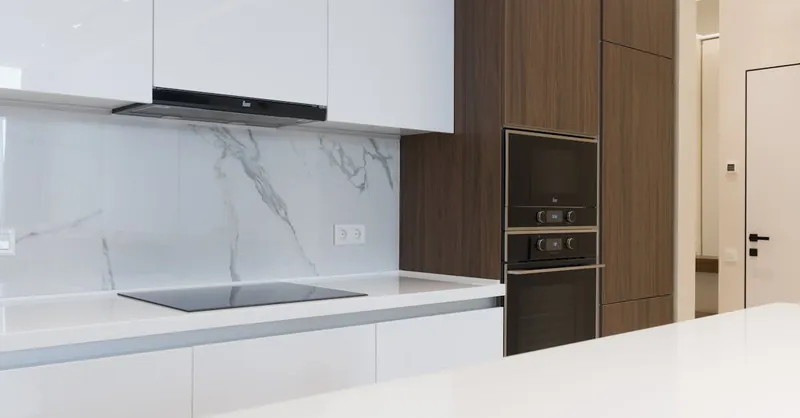 Contemporary clean kitchen with sleek appliances and wooden cabinetry, perfect for a new home.