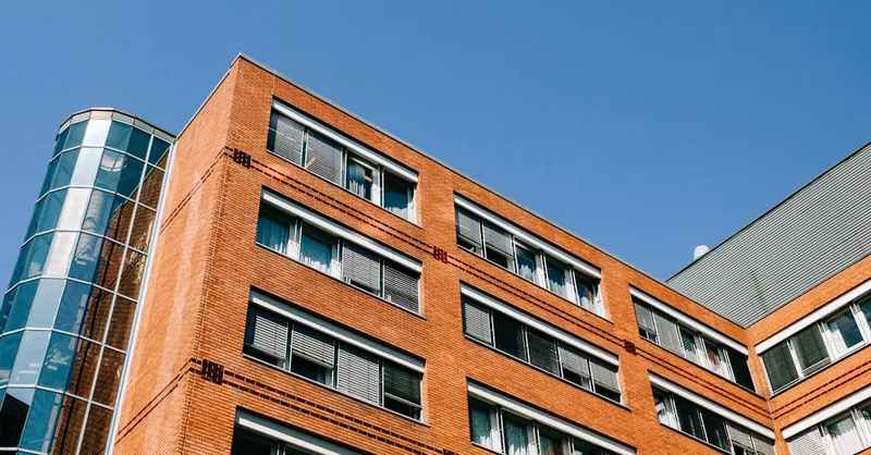 From below of contemporary high apartment building located in residential district against blue sky